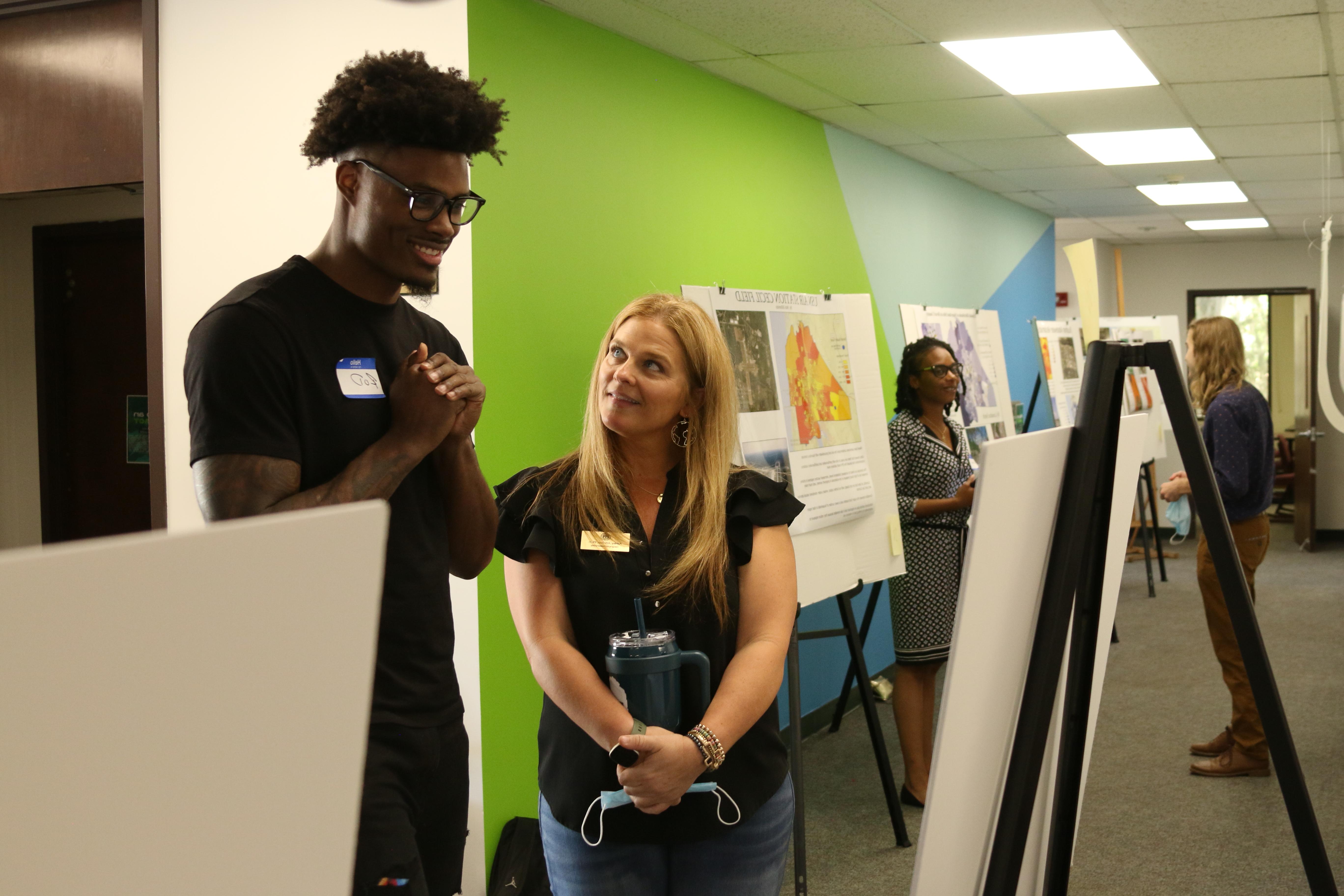 Dr. Ashley Johnson and male student looking at a map together in front of a colorful green and blue wall.